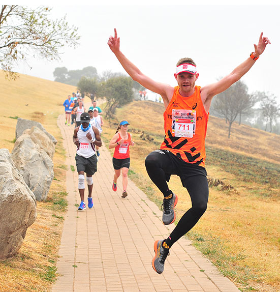 Runner celebrating with arms raised at the Wanderers Road Race